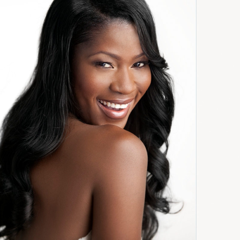 A black woman smiling with long black hair.