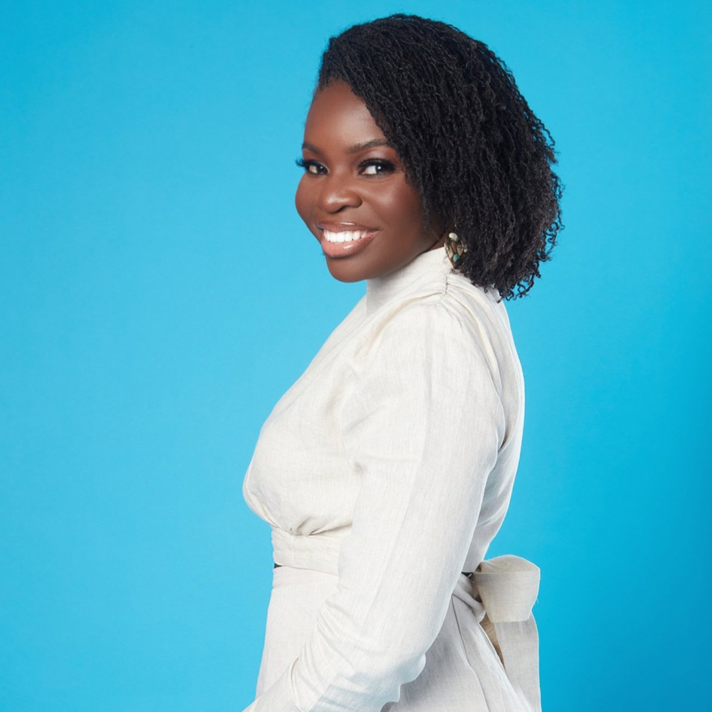 A young black woman posing for a photo on a blue background.