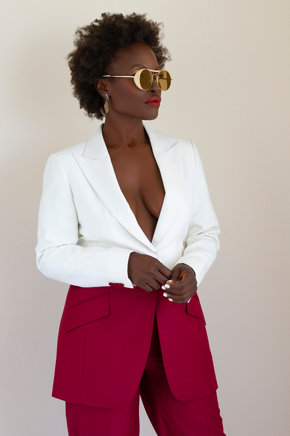 A woman wearing a white blazer and red pants.