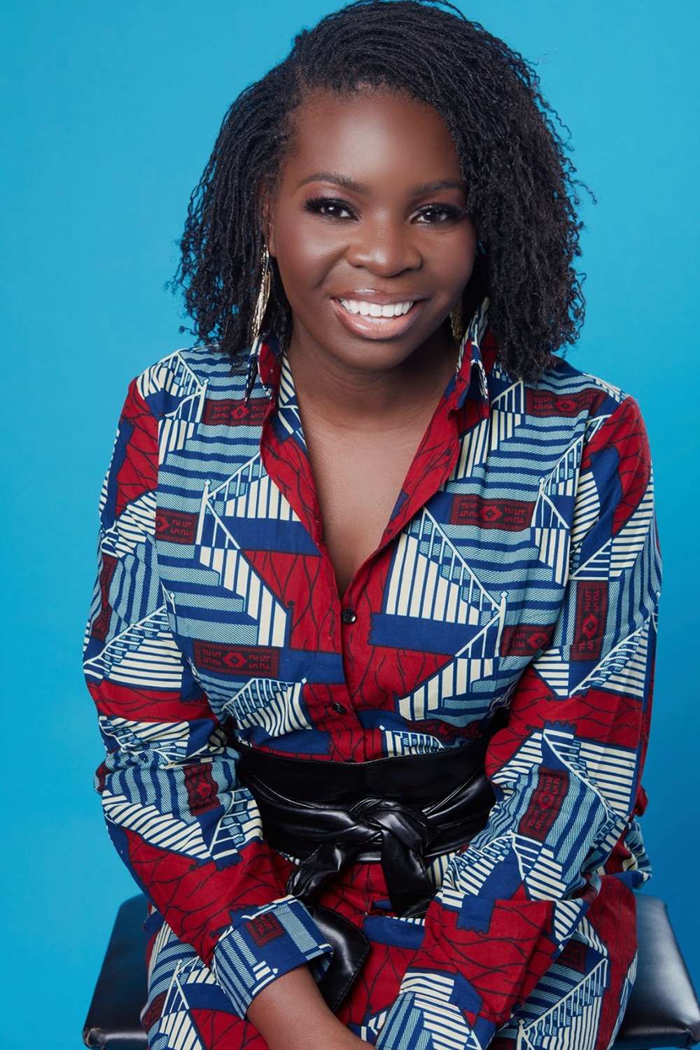 A young african woman smiling in front of a blue background.