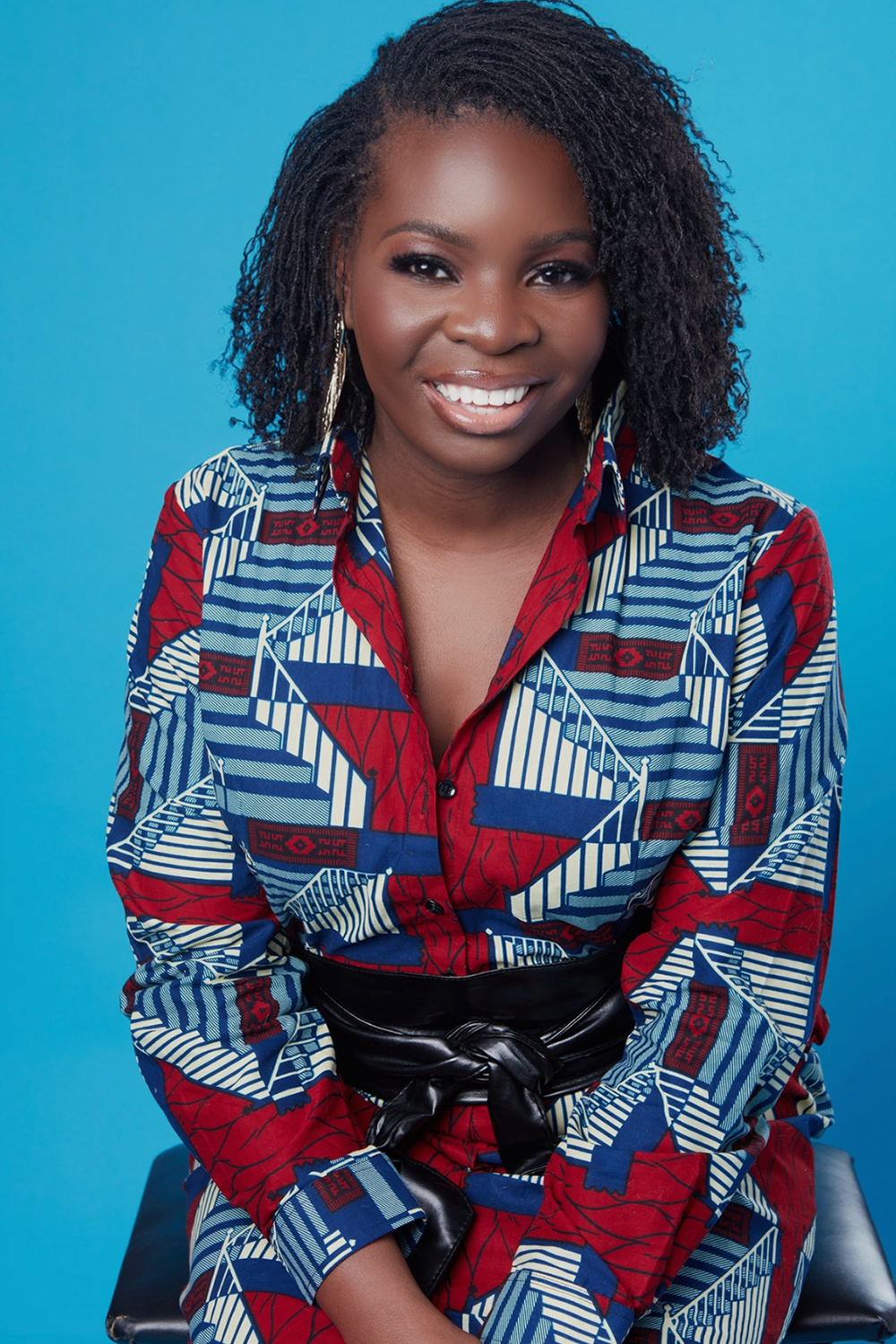 A young african woman smiling in front of a blue background. A young african woman smiling in front of a blue background.