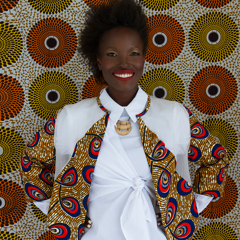 A woman is standing in front of a colorful wall.