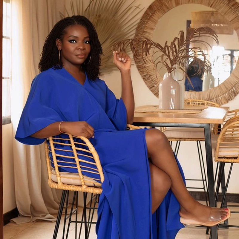 A woman in a blue dress sitting on a chair.