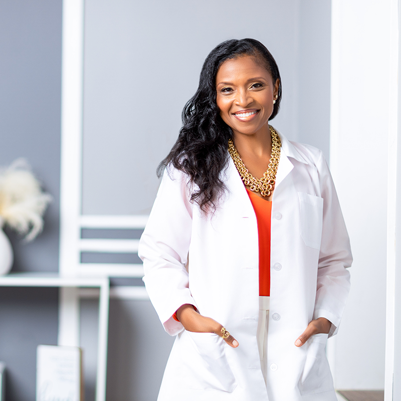 A woman in a white lab coat standing in a room.