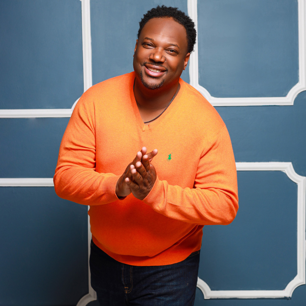 A man wearing an orange sweater. A man wearing an orange sweater.