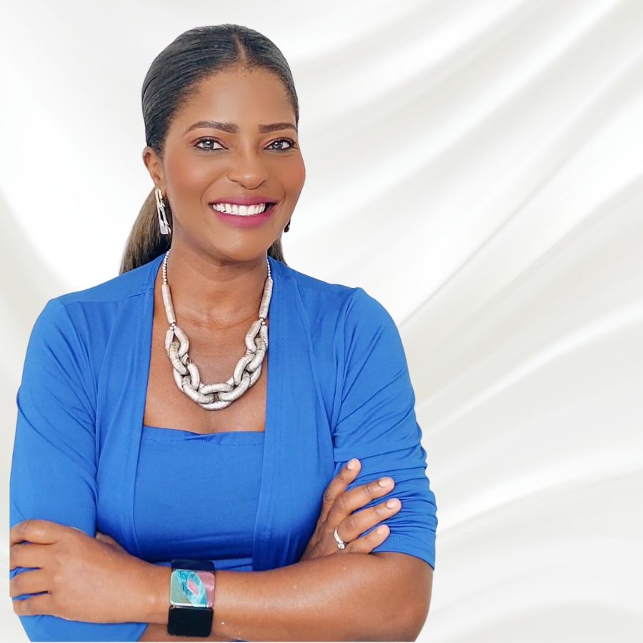 A smiling woman in a blue shirt with her arms crossed.